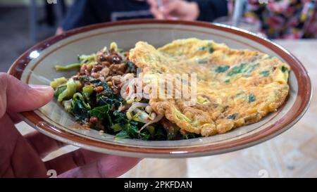 Nasi Pecel, traditionelle javanische Speisekarte mit würziger Erdnusssoße, gekochtem Gemüse und Spiegelei zum Frühstück oder Mittagessen Stockfoto