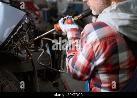 Mann am Arbeitsplatz in der Garage repariert Auto nach Unfall Stockfoto