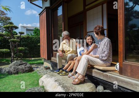 Ein älteres Paar und seine Enkel sitzen auf der Veranda Stockfoto