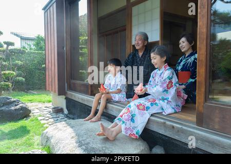 Großeltern und Enkelkinder sitzen auf der Veranda Stockfoto