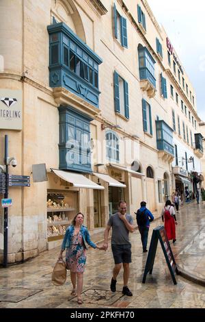 Valletta, Malta - 12. November 2022: Menschen, die nach dem Regen in Maltas Hauptstadt in einer nassen Fußgängerzone unterwegs sind Stockfoto