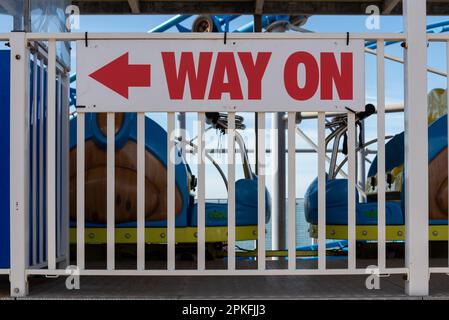 Eine hellrote Beschriftung auf einem Schild zeigt den Weg zu einer Fahrt in einem Vergnügungspark. Stockfoto