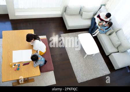 Mutter und Sohn zeichnen und Vater und Tochter lesen ein Bilderbuch Stockfoto