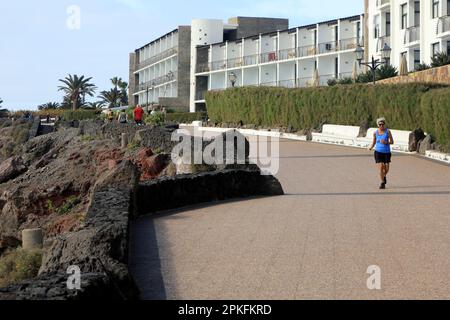 Eine ältere Dame läuft auf dem Küstenweg Richtung Las Coloradas, Playa Blanca, Lanzarote. Februar/März 2023. Stockfoto