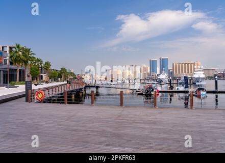 Blick auf den Creek in Richtung Deira mit großen Booten, die an der Promenade Al Seef in Dubai, Vereinigte Arabische Emirate, angelegt sind Stockfoto