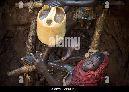 Kenia. 18. Februar 2023. Kinder des Turkana-Stammes, die Wasser aus einem Brunnen nehmen der Klimawandel verursacht in Ostafrika die schlimmste Dürre in seiner Geschichte: Es hat in dieser Region seit mehr als drei Jahren nicht mehr geregnet, und mehr als 36 Millionen Menschen sind mit den verheerenden Folgen einer Welle konfrontiert, die laut Prognosen nicht in absehbarer Zeit enden wird. In Turkana, nördlich von Kenia, kämpfen die Menschen, um diese schreckliche Dürre zu überleben. Kredit: SOPA Images Limited/Alamy Live News Stockfoto