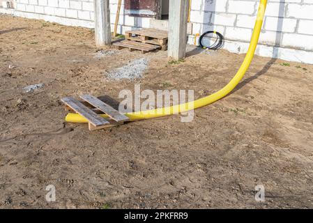 Gelbes PVC-Rohr mit einem Durchmesser von 100mm mm, das mit dem Ende der Dachrinne verbunden und gegen Wasser geschützt ist. Stockfoto