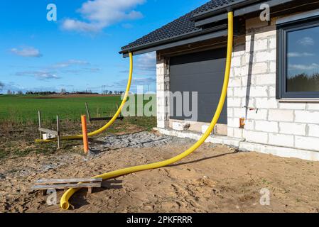 Gelbes PVC-Rohr mit einem Durchmesser von 100mm mm, das mit dem Ende der Dachrinne verbunden und gegen Wasser geschützt ist. Stockfoto