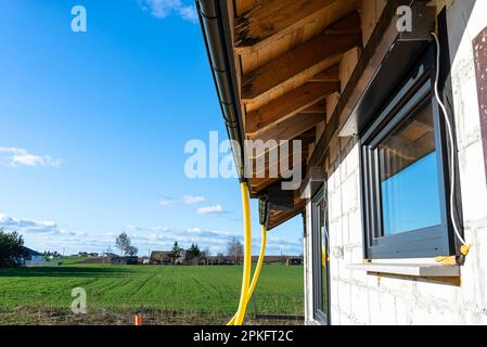 Gelbes PVC-Rohr mit einem Durchmesser von 100mm mm, das mit dem Ende der Dachrinne verbunden und gegen Wasser geschützt ist. Stockfoto