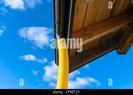 Gelbes PVC-Rohr mit einem Durchmesser von 100mm mm, das mit dem Ende der Dachrinne verbunden und gegen Wasser geschützt ist. Stockfoto