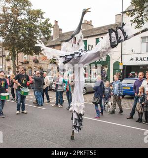 Die Straßenparade wird von einem selbstbewussten Stelzenläufer und Performer geleitet, das Skipton Puppet Festival 2015 Stockfoto