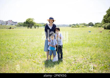 Geschwister und Mutter mit Insektennetzen auf der Wiese Stockfoto