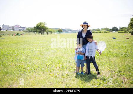 Geschwister und Mutter mit Insektennetzen auf der Wiese Stockfoto