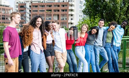 Glückliche Gruppe von multirassischen jungen Freunden, vielfältige Leute, die draußen vor der Kamera lächeln, internationale Gemeinschaft und fröhliche Menschen Stockfoto