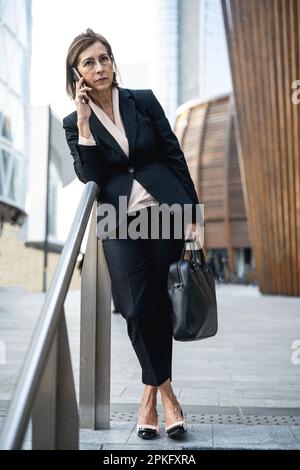 Reife und erfolgreiche Geschäftsfrau, die ihr Mobiltelefon für ein Arbeitsgespräch verwendet, Porträt einer Führungskraft in einer ernsthaften und entschlossenen Karriere Stockfoto