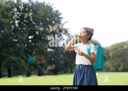 Ein Mädchen aus der Grundschule, das mit Seifenblasen spielt Stockfoto