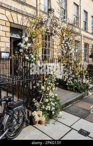 Vordertür und Außenansicht eines wunderschönen englischen Stadthauses in Bath, eingerichtet für Ostern. Blumen. Frühling. Fahrrad-Vordergrund. Stockfoto