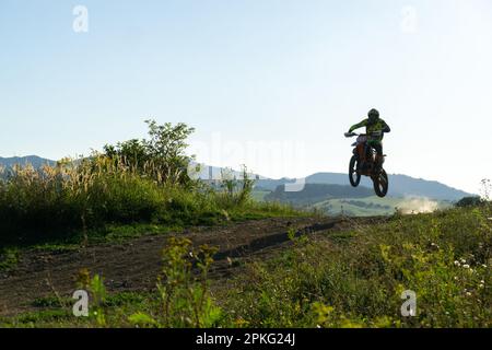 Motorradfahrer, der mit seinem Motorrad auf einer Motocross-Straße in der Natur fährt. Stockfoto