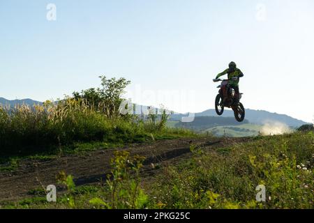 Motorradfahrer, der mit seinem Motorrad auf einer Motocross-Straße in der Natur fährt. Stockfoto