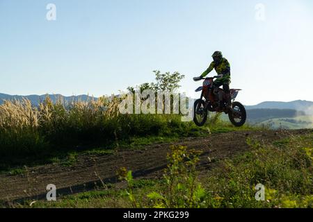 Motorradfahrer, der mit seinem Motorrad auf einer Motocross-Straße in der Natur fährt. Stockfoto