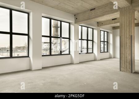 Ein leeres Zimmer mit großen Fenstern und viel Licht, das von der Sonne durch die Fensterscheiben hereinkommt Stockfoto