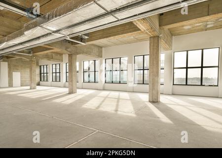 Ein leeres Bürogebäude mit vielen Fenstern und Licht, das von der Sonne durch das Panorama der Fenster hereinkommt Stockfoto