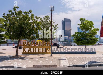 Dubai, Vereinigte Arabische Emirate - 31. März 2023: Blick über den Creek in Richtung Deira mit Hashtag-Schild für Ramadan auf der Promenade von Al Seef Stockfoto