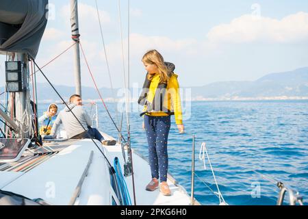 Fahrt Segeltörn auf einer luxuriösen Sportyacht. Bootsfahrt mit der Familie im Sommer. Kinder, Matrosenjunge, die in einer kleinen Rettungsweste segelt. Ozean-Shi Stockfoto