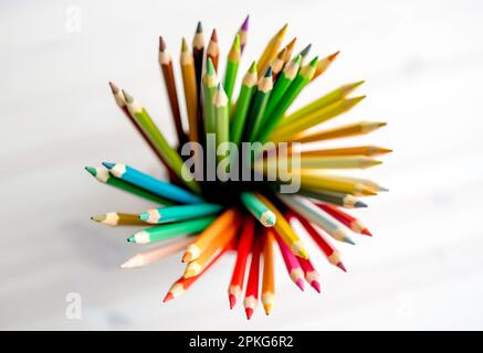 Scharfe, farbenfrohe Bleistifte auf Aquarellpapier, Blick von oben. Mehrfarbige Buntstifte sorgen für künstlerische Inspiration Stockfoto