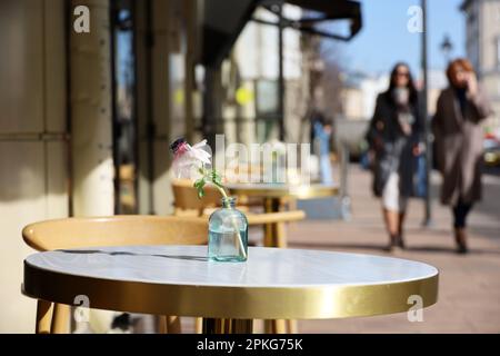 Straßencafe in der Stadt mit leeren Tischen draußen im Hintergrund für Spaziergänger. Blumen auf runden Tischen an sonnigen Tagen Stockfoto
