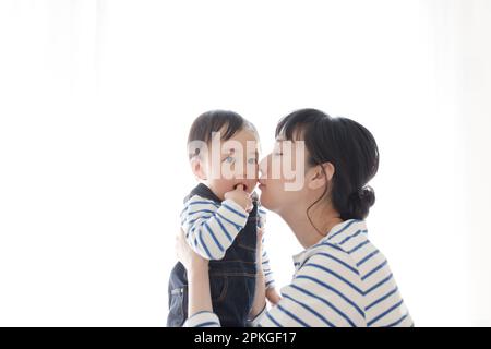 Das Baby wird von der Mutter getragen und geküsst Stockfoto