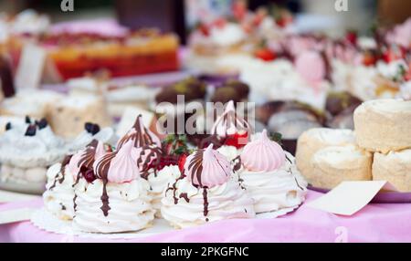 Pavlova Desserts mit Erdbeeren und Schokolade verziert zusammen mit anderen Desserts auf dem Tisch der lokalen Süßwaren im Prager Street Food ma Stockfoto