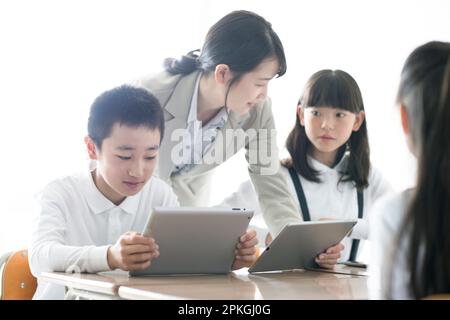 Eine Grundschülerin, die von ihrem Lehrer AR ein Programm lernt Stockfoto