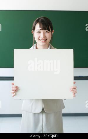 Lehrer, der das Whiteboard hält und lächelt Stockfoto