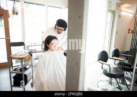 Eine Frau, die sich von einem Friseur frisieren lässt Stockfoto