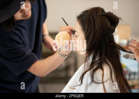 Eine Frau, die sich Haare machen und sich schminken lässt Stockfoto