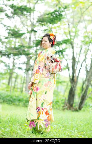 Eine Frau im Kimono, die in den Wald zurückblickt Stockfoto