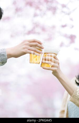 Hände, die vor Kirschblüten toasten Stockfoto