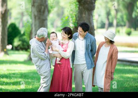 Eine Familie von drei Generationen, die sich an einer Reihe von Pappelbäumen unterhält Stockfoto