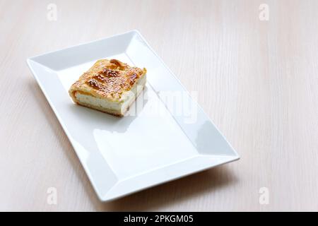 Süße Bäckerei - Hüttenkäse auf grauem Steinhintergrund. Gebackener Käsekuchen im rustikalen Stil auf einem Steintisch. Ästhetische Zusammensetzung mit Hüttenkuchen. Hüttenkäse-Torte. Hochwertiges Foto Stockfoto