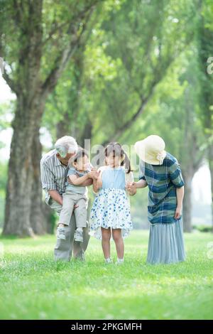 Großeltern und Enkel, die sich in einer Reihe von Pappelbäumen unterhalten Stockfoto