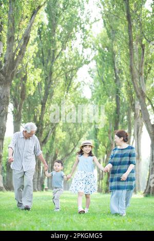 Großeltern und Enkelkinder laufen entlang einer Reihe von Pappelbäumen Stockfoto