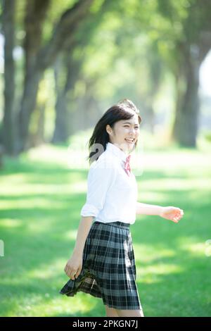 Eine Studentin, die an einer Reihe von Pappelbäumen entlang läuft Stockfoto