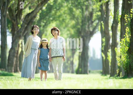 Eine Familie von drei Generationen lächelt auf einer Reihe von Pappelbäumen Stockfoto