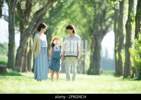 Eine Familie von drei Generationen, die in einer Reihe von Pappelbäumen plaudert Stockfoto