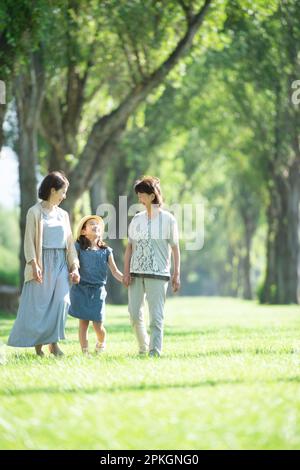 Eine Familie von drei Generationen, die in einer Reihe von Pappelbäumen plaudert Stockfoto