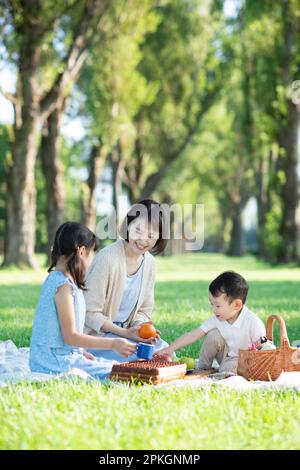Eltern und Kinder machen ein Picknick an einer Reihe von Pappelbäumen Stockfoto