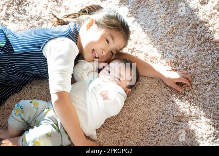 Schwestern liegen auf dem Teppich Stockfoto