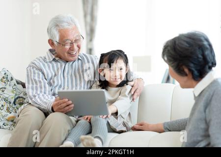 Großeltern und Enkelkindern, die sich einen Tablet-PC ansehen Stockfoto