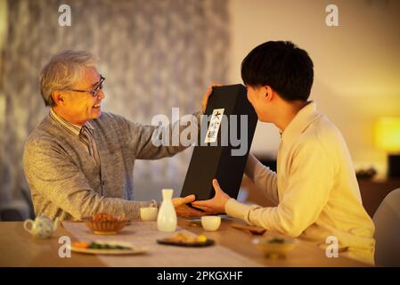 Vater bekommt ein Sake-Geschenk von seinem Sohn Stockfoto